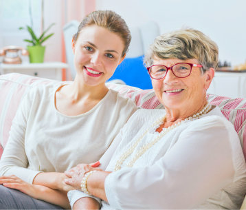 Elder woman sitting on a couch with her young caregiver