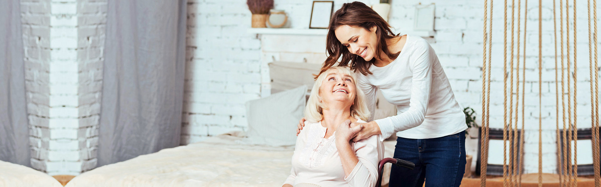 Joyful delighted old woman sitting in wheelchair and lookign at her caregiver