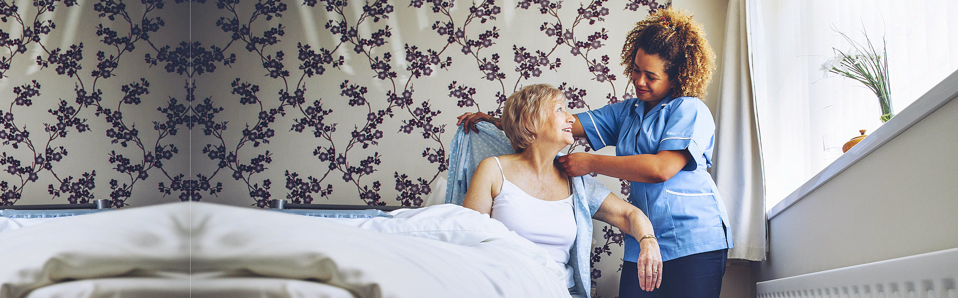 Home caregiver helping a senior woman get dressed in her bedroom