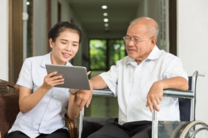 caregiver showing tablet to elderly man